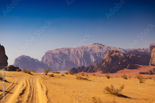 Wadi Rum w Jordanii. Pustynna droga wiodąca do skalnych gór.