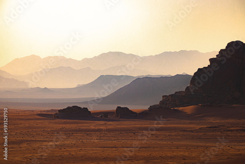 Wadi Rum w Jordanii. Widok z pustyni na góry w oddali oświetlone słońcem. 