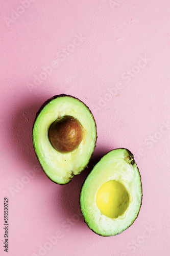 An avocado cutted on a pink background. High contrast