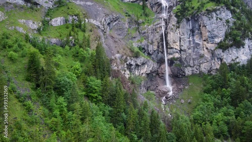 Aerial Descending Drone view of Almenbachfall waterfall in Kandertal flowing among pine trees and alpine rocks, Kandersteg Berner Oberland Switzerland photo