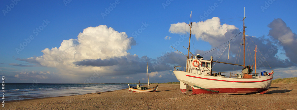 Fishing boat on the shore of the Jammerbugten, Denmark. Summer clouds.