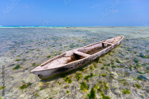 The scene depicts an aged wooden boat gently floating on the crystal-clear water