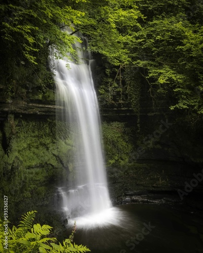 Scenic vertical shot of the Glencar waterfall in a forest in Sligo  Ireland