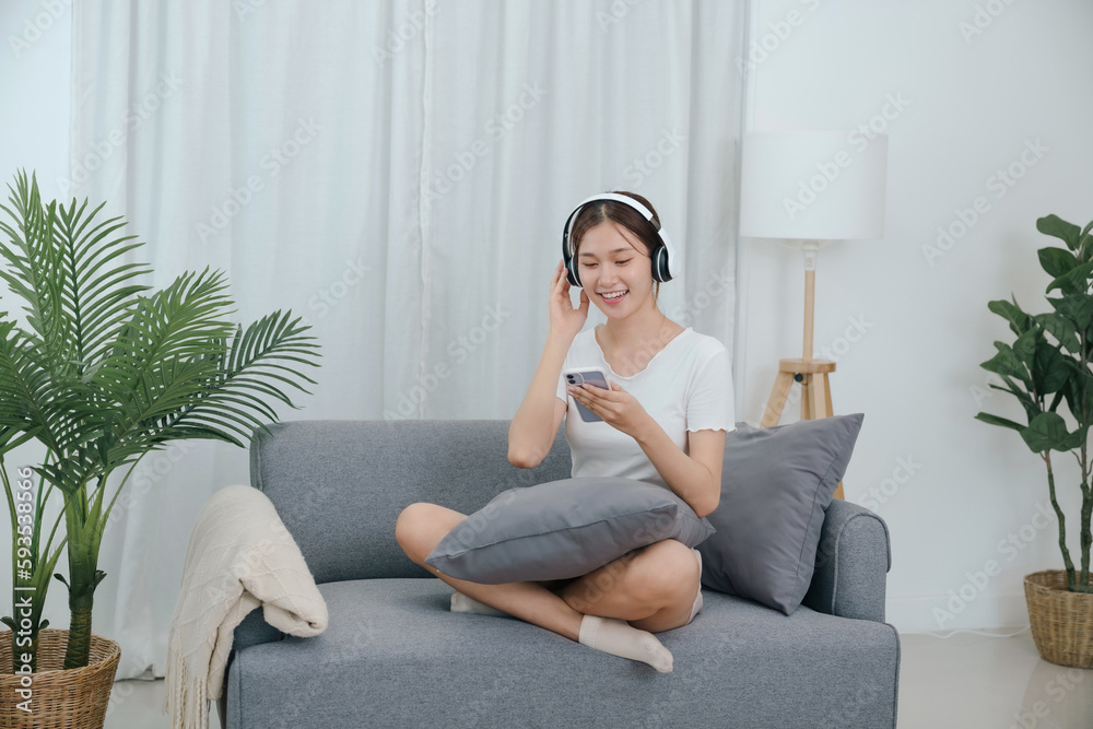 Obraz premium Young asian woman with headphones relaxing at home. listening to music