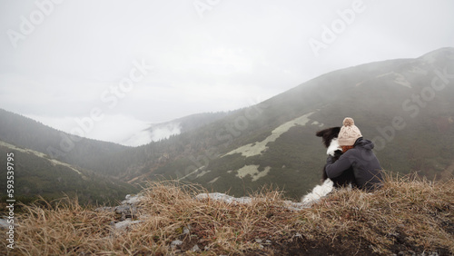 young red head woman sitting on a mountain top with czech mountain dog in the fog photo