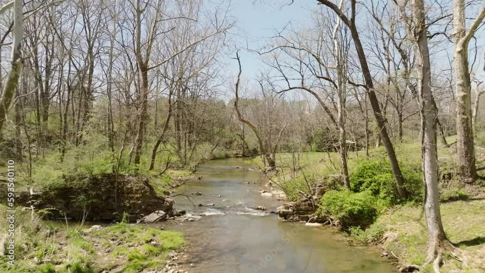 Aerial view of natural creek flowing in spring with moving water through trees in slow motion. Aerial view of natural creek flowing in spring with moving water through trees in slow motion.