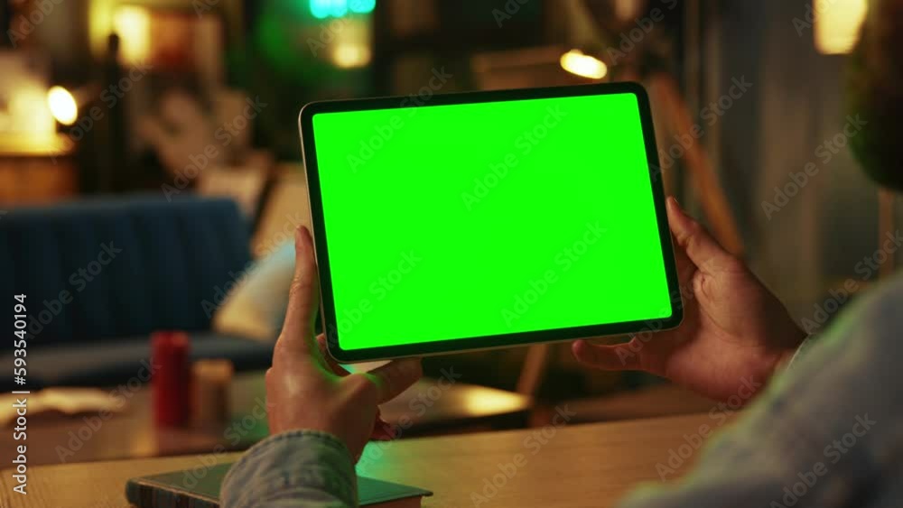 In dark room hands man holding scrolling and tapping on tablet computer with horizontal green screen. Mock up. Online. Technology In dark room hands man holding scrolling and tapping on tablet computer with horizontal green screen. Mock up. Online. Technology