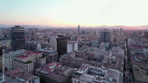 Establishing aerial view flying over Santiago sunset cityscape towards downtown Torre Entel tower and Andes mountains skyline photo