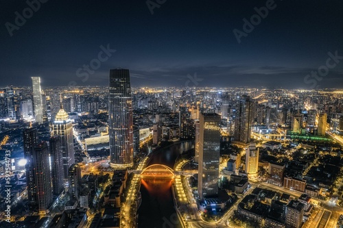 Drone modern cityscape view with a river and illuminated buildings at night