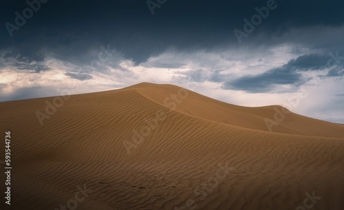 Beautiful shot of sand dune landscape with dark clouds in the desert © Yang6/Wirestock Creators