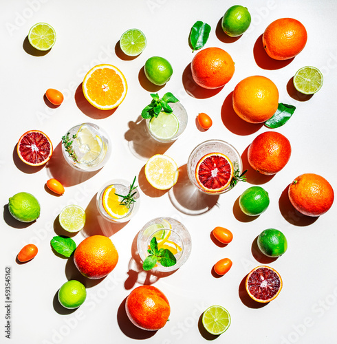 Gin tonic citrus and herb cocktails set, top view. Assortment of summer drinks for cocktail party. Light beige background, bright fruits, hard light, shadow pattern