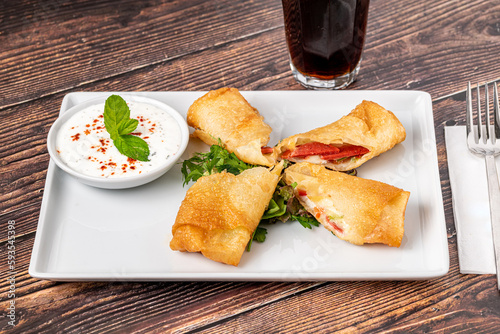 Pacanga pastry with salad and yogurt sauce on a white porcelain plate photo