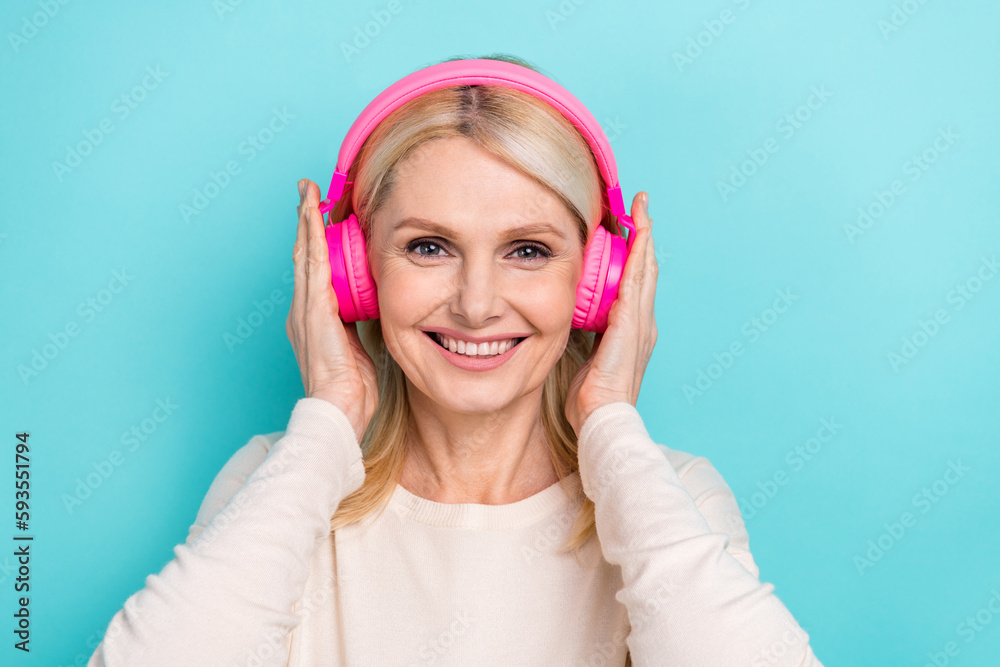 Portrait of old woman attractive blonde hair wear white shirt touch wireless headphones music playlist isolated on aquamarine color background Portrait of old woman attractive blonde hair wear white shirt touch wireless headphones music playlist isolated on aquamarine color background