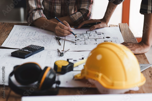 Architect and Engineer working with blueprints for architectural plan, engineer sketching a construction project, green energy concept