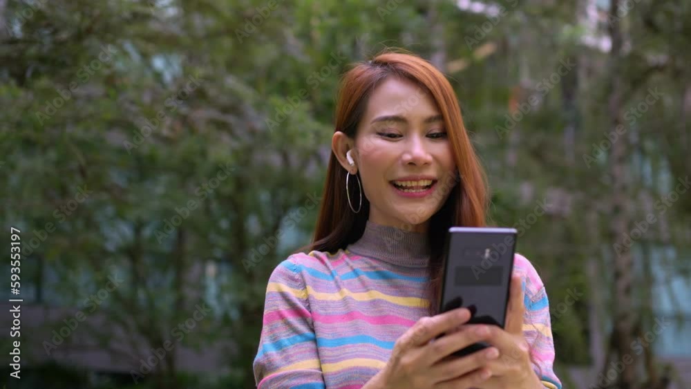 A smiling female tourist talking via text message link on the park in the hotel. Feel happy. text message chat. Close up happy woman text message chatting online on mobile phone outdoor. A smiling female tourist talking via text message link on the park in the hotel. Feel happy. text message chat. Close up happy woman text message chatting online on mobile phone outdoor.