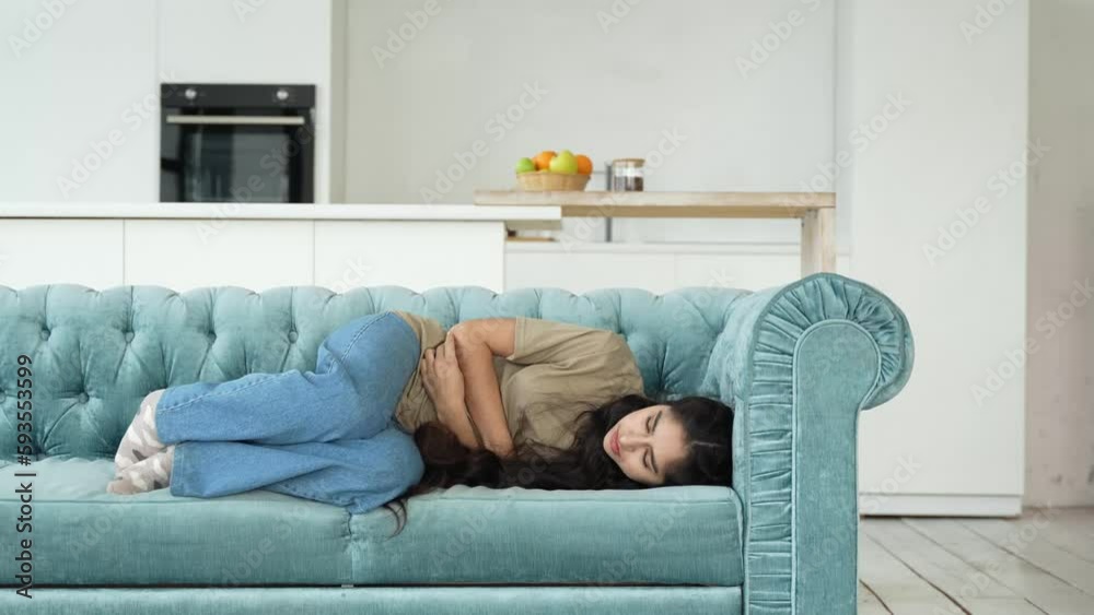 Sick girl with stomach ache menstrual pain and bad feeling lays down on