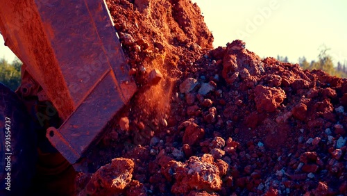 Follow close up shot of dump track dumping red and blue clay in pile. Then it drives away. The stones are crumbling. 25perc slow motion. 4k.