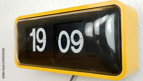 Vintage Yellow FLIP CLOCK running fast 60s 70s design timelapse turning over industrial with large dial evening time mounted on a white wall isolated on white background 
