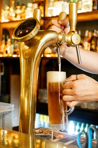 Vertical closeup of the bartender pouring beer from a beer tap. photo