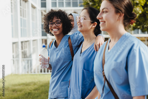Diverse, happy female students coming from class in medical scrubs