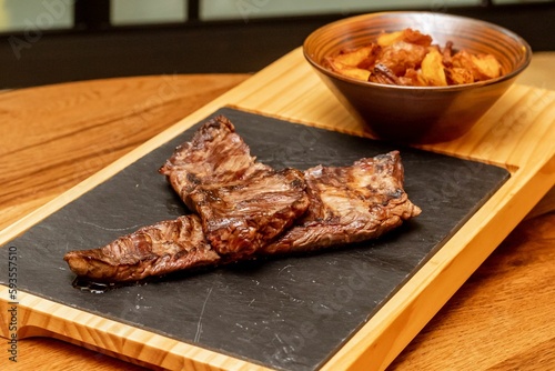 Pices of steak with fried potato on the wooden board. photo