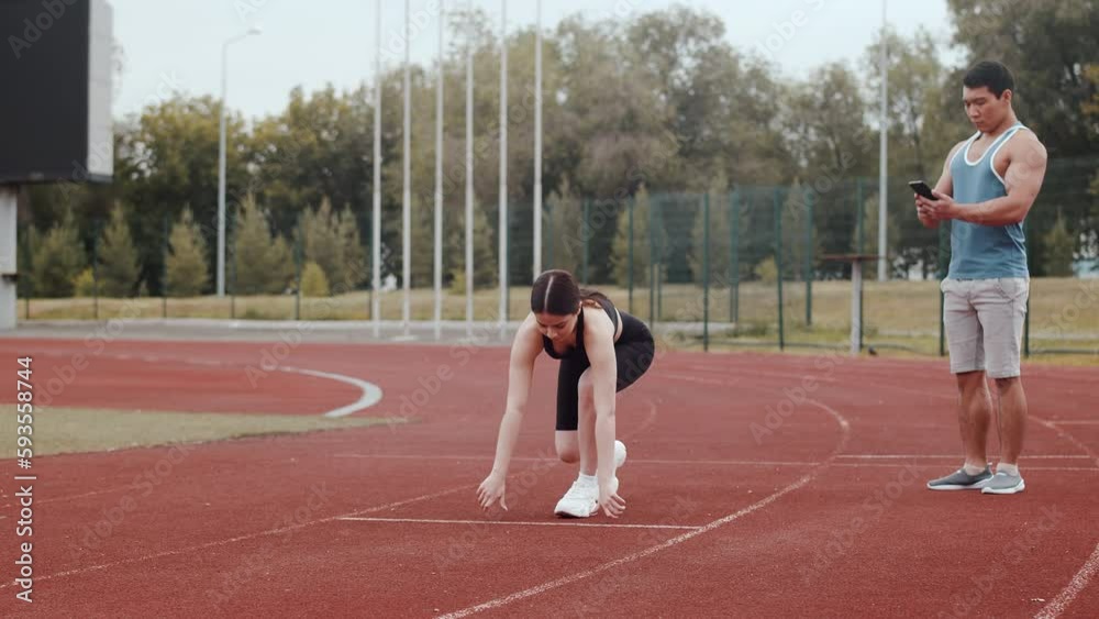 Young caucasian female athlete starts running from a low-start position ...