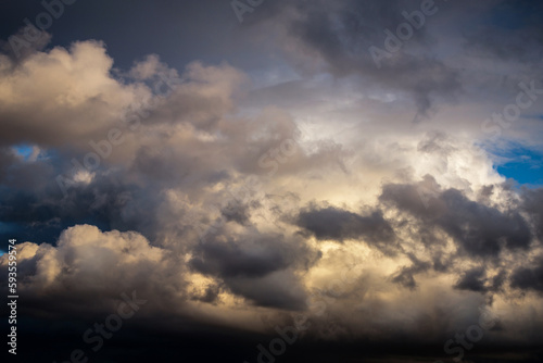 Storm cloudy dramatic sky with dark rain grey cumulus cloud in sunlight and blue sky background texture, thunderstorm, heaven