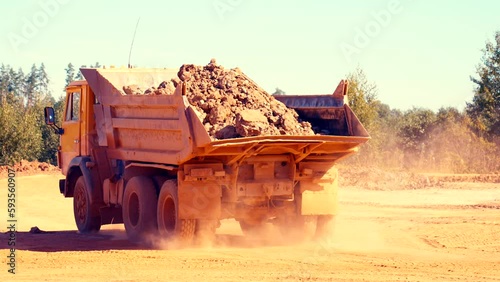 Following shot of a dump truck driving away. Dust and smoke in the air. 4k.