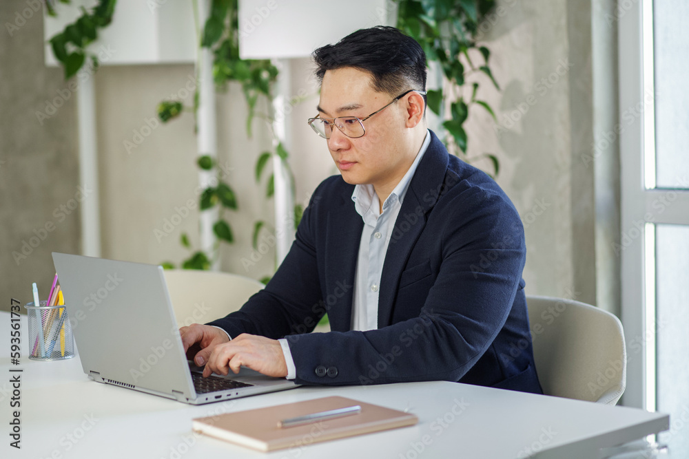 Asian businessman working in office, using laptop. Human resources. Finance concept. Multiracial Asian businessman working in office, using laptop. Human resources. Finance concept. Multiracial