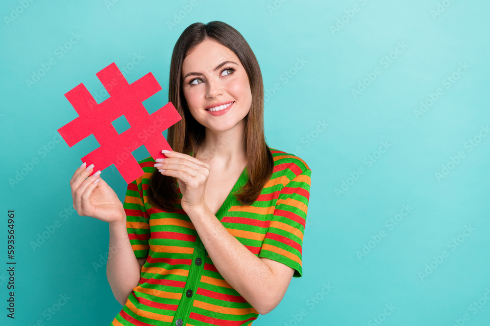 Photo of dreamy cute lady wear striped cardigan holding hash tag looking empty space isolated turquoise color background Photo of dreamy cute lady wear striped cardigan holding hash tag looking empty space isolated turquoise color background