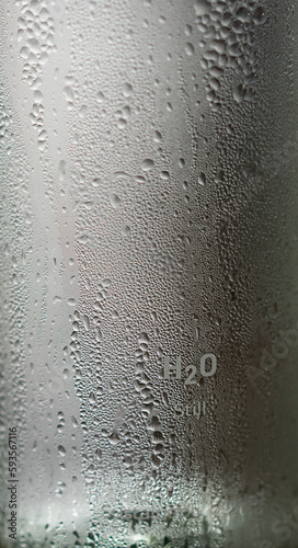 Misted glass bottle of water with inscription on the bottle H2O still, sustainably bottled.