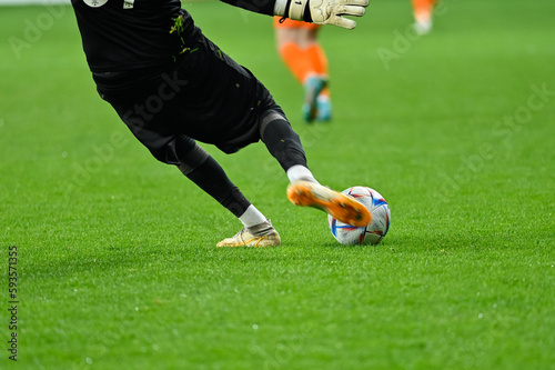 Football goalkeeper kicks ball. Player s legs and the ball during soccer match.