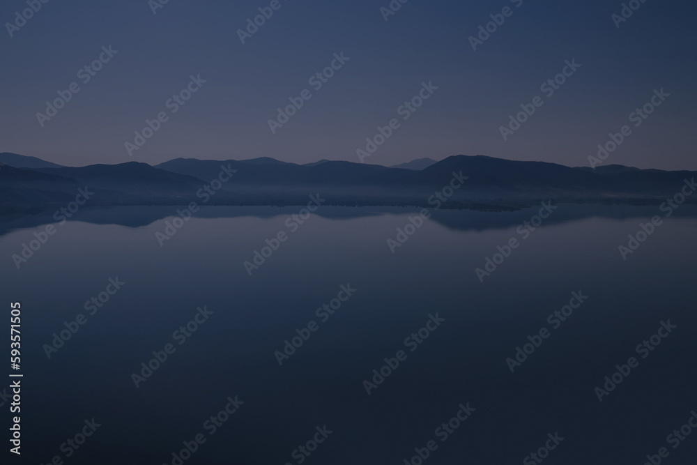 Silhouette of mountains near lake at the early morning with clear sky