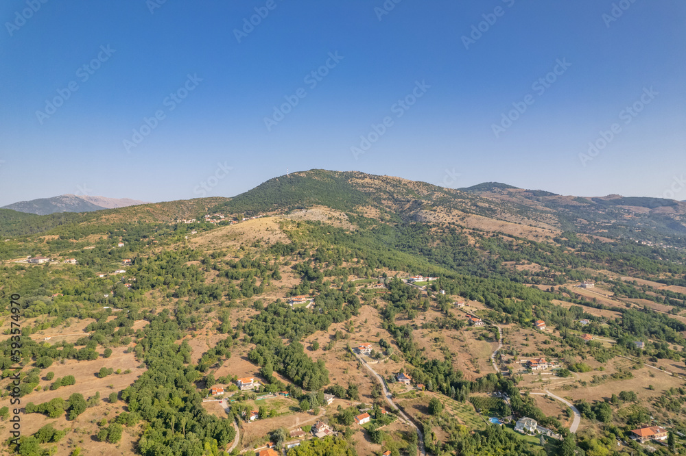 Aerial view of traditional village with rural houses, buildings, highway bridge, countryside roads in Greece. Drone, copter view