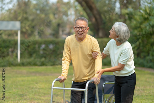 A wife helping her elderly husband patient use a walker to learn to walk. Elderly couple. Asian elderly couple giving love to each other smiling happily. Love and care for each other. © amnaj