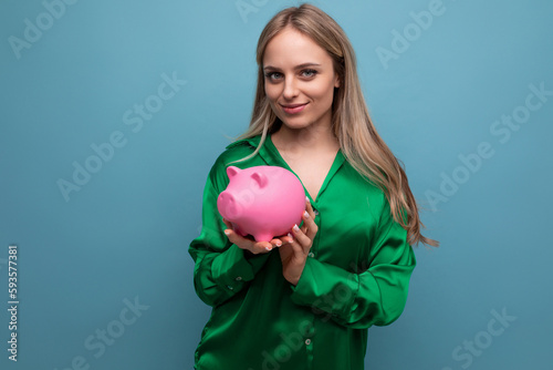 european stylish attractive blonde girl with a piggy bank on a blue background