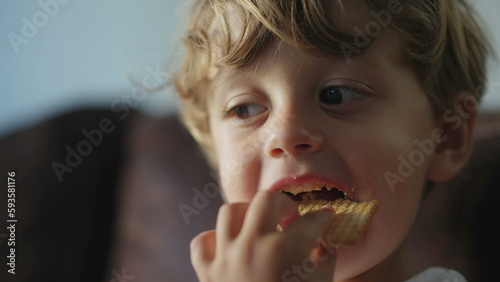 Happy child snacking cookie dessert. One small boy closeup face eating sugar carb food