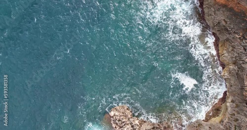 Flight over a cliff. Drone shot with waves against a cliff