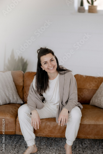 Dunkelhaarige Frau, 40, sitzt gemütlich Zuhause auf der Couch