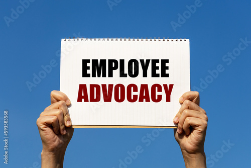 Obraz na plátne Employee advocacy text on notebook paper held by 2 hands with isolated blue sky background