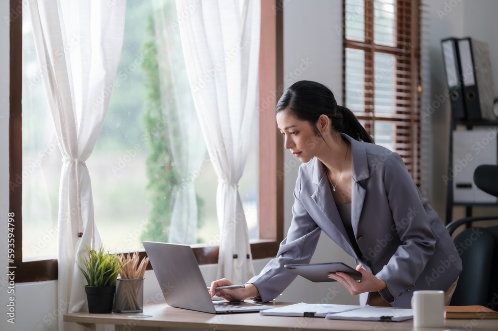 Creative Asian young woman working on laptop in her office. Creative Asian young woman working on laptop in her office.