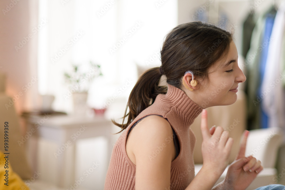 Portrait of teenage girl with hearing aid in her room.