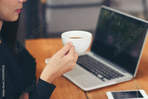 Remote working at Home office Concept. Businesswoman working online via laptop and drink coffee. Asian young entrepreneur watching webinars and talking during meeting video conferences calls with team