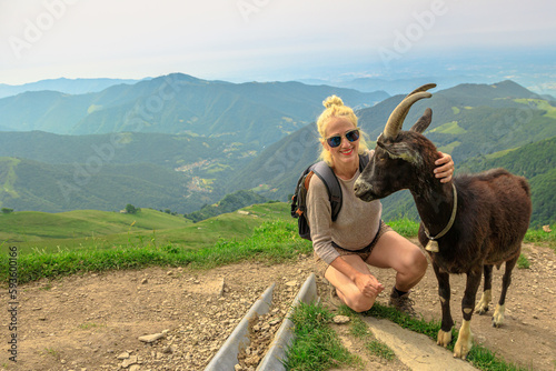 backpacker tourist Woman playing with a goat in Monte Generoso peak. Top of Mendrisio district of Switzerland in ticino canton. photo