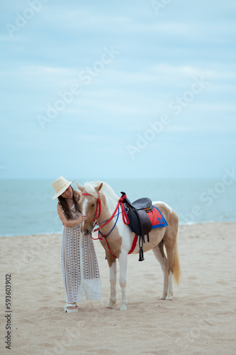 Fototapeta Naklejka Na Ścianę i Meble -  Young long hair woman in white dress riding horse on seascape background