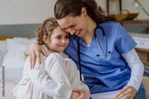 Foto Young doctor hugging little girl in hospital room.