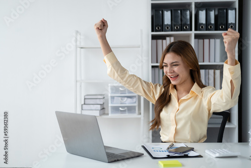 Young happy Asian business woman feeling overjoyed after receiving the good news from company.