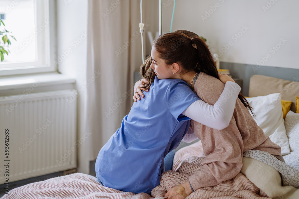 Obraz premium Young doctor hugging teenage girl in hospital room.