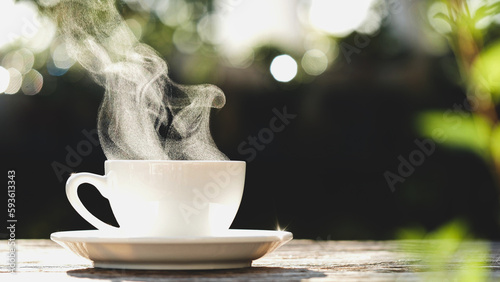 Coffee Cup. Close-up natural steam smoke of coffee from hot coffee cup on old wooden table in morning warm sunshine flare, outdoor view background. Concept hot drink, espresso, breakfast