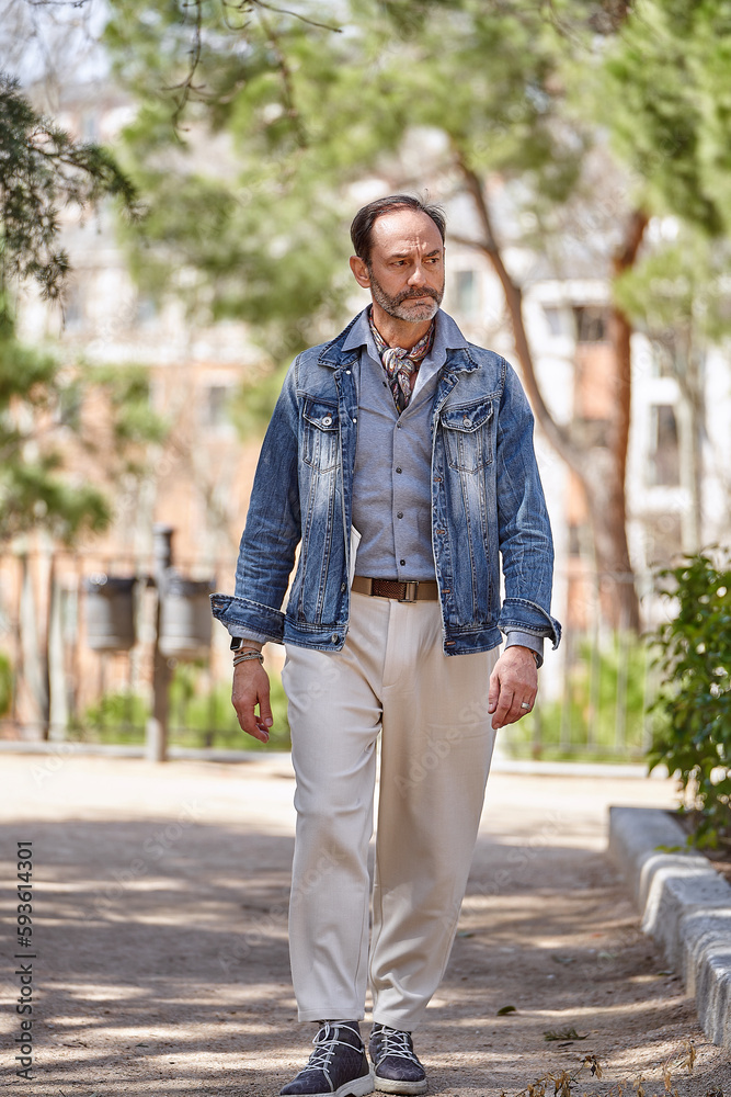 Retired man savoring fresh air and blooming nature during a leisurely stroll in the park Retired man savoring fresh air and blooming nature during a leisurely stroll in the park